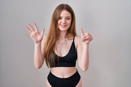 Téléchargez les photos : Young caucasian woman wearing lingerie showing and pointing up with fingers number six while smiling confident and happy. - en image libre de droit