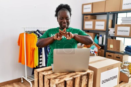 Téléchargez les photos : Jeune femme afro-américaine portant un uniforme de bénévole parlant en langage des signes sourd au centre de charité - en image libre de droit