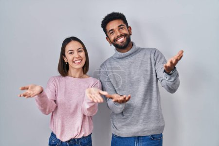 Téléchargez les photos : Young hispanic couple standing together smiling cheerful offering hands giving assistance and acceptance. - en image libre de droit