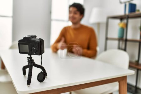 Téléchargez les photos : Jeune homme hispanique ayant un appel vidéo en utilisant une caméra assise sur le canapé à la maison. - en image libre de droit