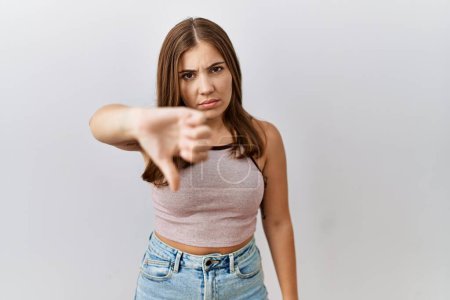 Photo for Young brunette woman standing over isolated background looking unhappy and angry showing rejection and negative with thumbs down gesture. bad expression. - Royalty Free Image