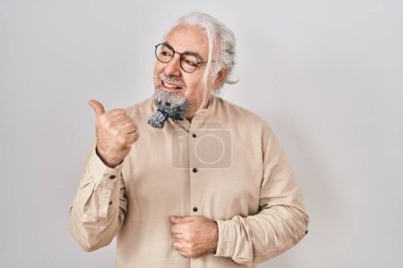 Photo for Middle age man with grey hair standing over isolated background smiling with happy face looking and pointing to the side with thumb up. - Royalty Free Image