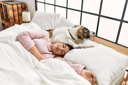 Photo for Young woman sleeping lying on bed with dog at bedroom - Royalty Free Image