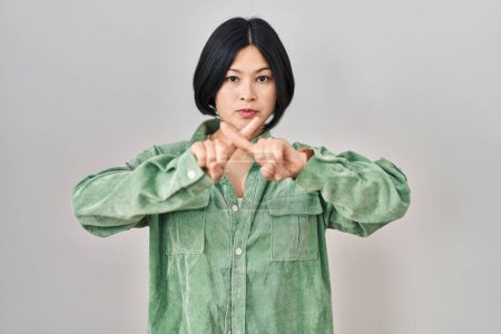 Foto de Joven asiática mujer de pie sobre blanco fondo rechazo expresión cruzar dedos haciendo negativo signo - Imagen libre de derechos