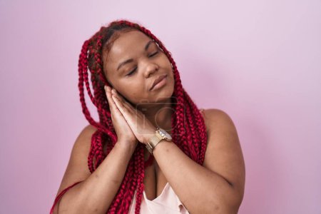 Photo for African american woman with braided hair standing over pink background sleeping tired dreaming and posing with hands together while smiling with closed eyes. - Royalty Free Image