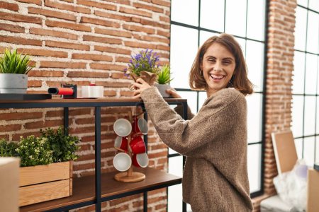 Photo for Young caucasian woman smiling confident holding lavender plant pot at new home - Royalty Free Image