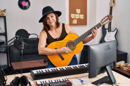 Photo for Middle age woman musician playing classical guitar at music studio - Royalty Free Image