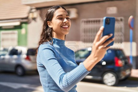 Foto de Joven afroamericana americana sonriendo confiada teniendo video llamada en la calle - Imagen libre de derechos