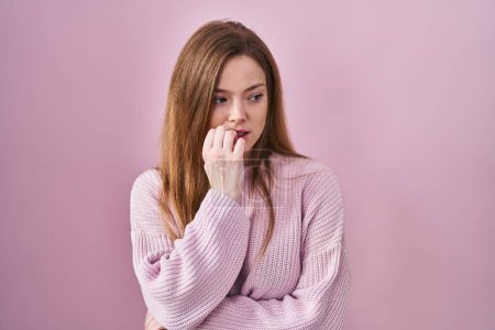 Photo for Young caucasian woman standing over pink background looking stressed and nervous with hands on mouth biting nails. anxiety problem. - Royalty Free Image