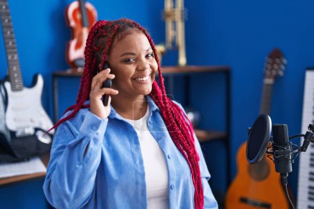 Foto de African american woman artist talking on smartphone at music studio - Imagen libre de derechos