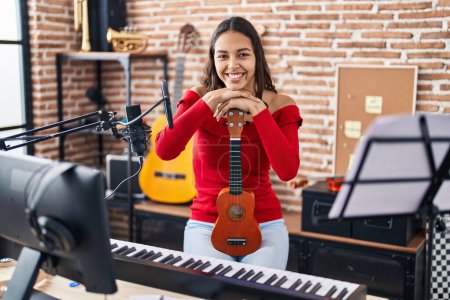 Téléchargez les photos : Jeune musicienne afro-américaine souriante confiante tenant ukelele au studio de musique - en image libre de droit