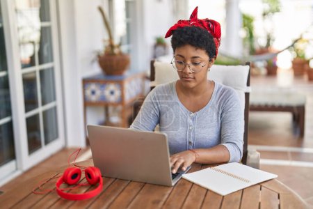 Photo for African american woman sitting on table studying at home terrace - Royalty Free Image