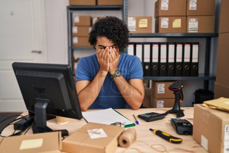 Photo for Hispanic man with curly hair working at small business ecommerce with sad expression covering face with hands while crying. depression concept. - Royalty Free Image