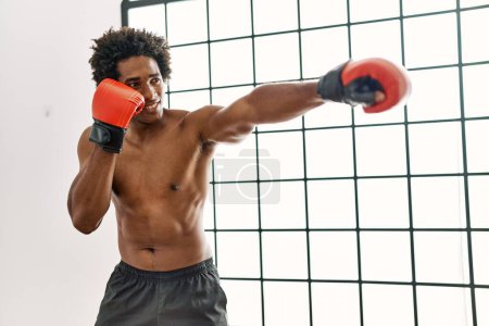 Foto de Joven afroamericano hombre sonriendo feliz boxeo en el gimnasio - Imagen libre de derechos