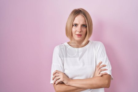 Foto de Young caucasian woman standing over pink background skeptic and nervous, disapproving expression on face with crossed arms. negative person. - Imagen libre de derechos