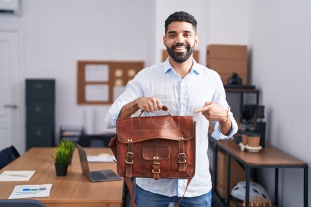 Téléchargez les photos : Homme hispanique avec barbe travaillant au bureau tenant porte-documents souriant heureux pointant avec la main et le doigt - en image libre de droit