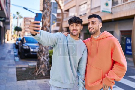 Foto de Dos hombre pareja haciendo selfie por teléfono inteligente en la calle - Imagen libre de derechos