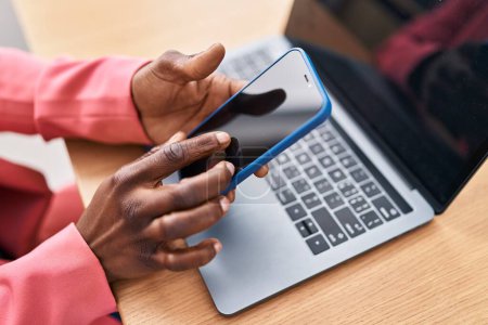 Téléchargez les photos : Femme afro-américaine travailleur d'affaires en utilisant un ordinateur portable et smartphone au bureau - en image libre de droit