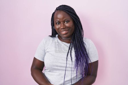 Téléchargez les photos : Jeune femme africaine debout sur fond rose avec les mains jointes et les doigts croisés souriant détendu et joyeux. succès et optimisme - en image libre de droit