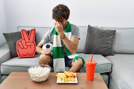 Photo for Young hispanic man football hooligan cheering game at home tired rubbing nose and eyes feeling fatigue and headache. stress and frustration concept. - Royalty Free Image