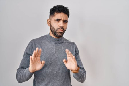 Photo for Hispanic man with beard standing over white background moving away hands palms showing refusal and denial with afraid and disgusting expression. stop and forbidden. - Royalty Free Image