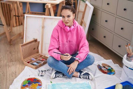 Téléchargez les photos : Jeune artiste assise sur le sol dessin au studio d'art - en image libre de droit