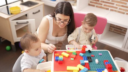 Photo for Teacher and preschool students playing with construction blocks and cars sitting on table at kindergarten - Royalty Free Image