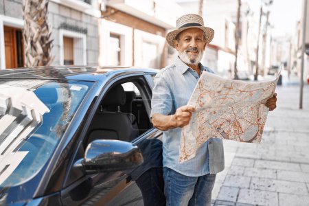Foto de Senior hombre de pelo gris turista celebración de mapa de la ciudad de pie en coche en la calle - Imagen libre de derechos