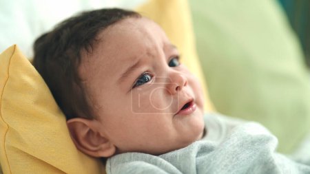 Foto de Adorable bebé hispano acostado en la cama llorando en el dormitorio - Imagen libre de derechos