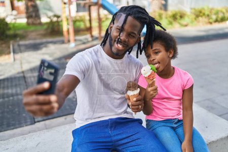 Téléchargez les photos : Père et fille manger de la crème glacée faire selfie par smartphone au parc - en image libre de droit