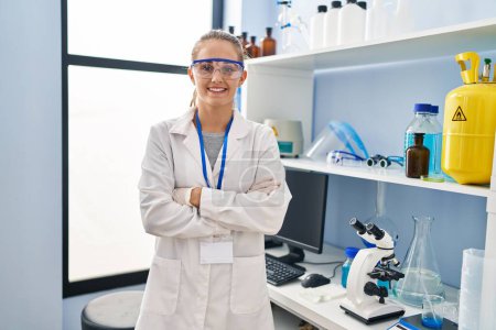 Téléchargez les photos : Young blonde woman wearing scientist uniform standing with arms crossed gesture at laboratory - en image libre de droit