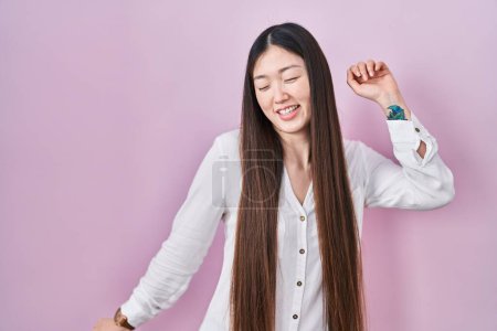 Photo for Chinese young woman standing over pink background dancing happy and cheerful, smiling moving casual and confident listening to music - Royalty Free Image