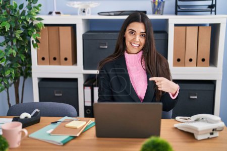 Téléchargez les photos : Jeune femme brune travaillant au bureau souriant heureux pointant avec la main et le doigt - en image libre de droit