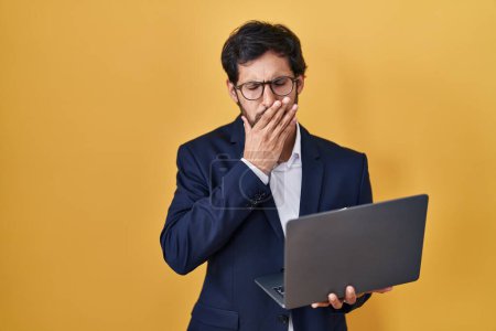 Foto de Handsome latin man working using computer laptop bored yawning tired covering mouth with hand. restless and sleepiness. - Imagen libre de derechos