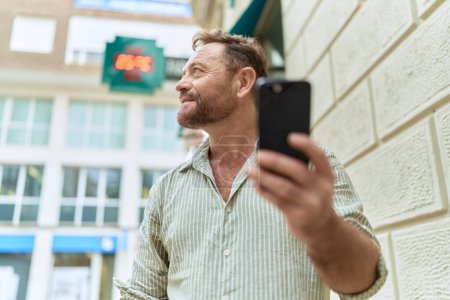 Téléchargez les photos : Homme du moyen âge utilisant un smartphone avec une expression sérieuse à la pharmacie - en image libre de droit
