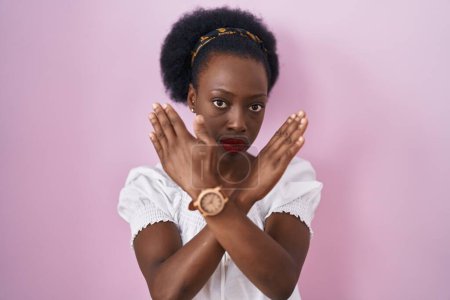 Téléchargez les photos : African woman with curly hair standing over pink background rejection expression crossing arms doing negative sign, angry face - en image libre de droit