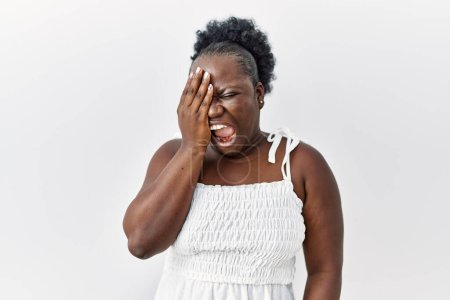 Foto de Mujer africana joven de pie sobre fondo blanco aislado bostezando cansado cubriendo media cara, ojos y boca con la mano. cara duele en el dolor. - Imagen libre de derechos