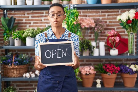 Photo for African american woman working at florist holding open sign making fish face with mouth and squinting eyes, crazy and comical. - Royalty Free Image