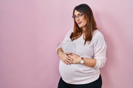 Téléchargez les photos : Pregnant woman standing over pink background smiling looking to the side and staring away thinking. - en image libre de droit