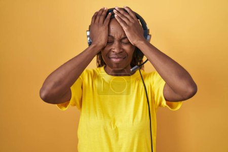 Photo for African american woman listening to music using headphones suffering from headache desperate and stressed because pain and migraine. hands on head. - Royalty Free Image