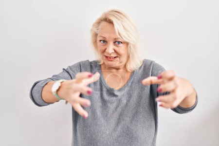 Photo for Middle age caucasian woman standing over white background shouting frustrated with rage, hands trying to strangle, yelling mad - Royalty Free Image