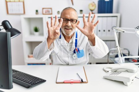 Photo for Mature doctor man at the clinic showing and pointing up with fingers number nine while smiling confident and happy. - Royalty Free Image