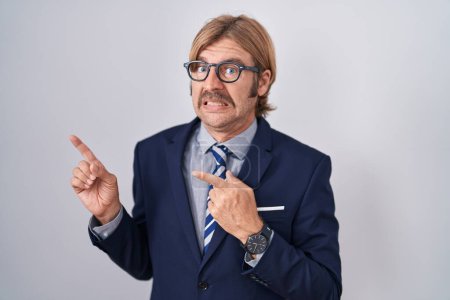 Photo for Caucasian man with mustache wearing business clothes pointing aside worried and nervous with both hands, concerned and surprised expression - Royalty Free Image