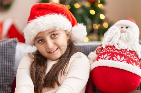Photo for Adorable hispanic girl smiling confident sitting on sofa by christmas tree at home - Royalty Free Image