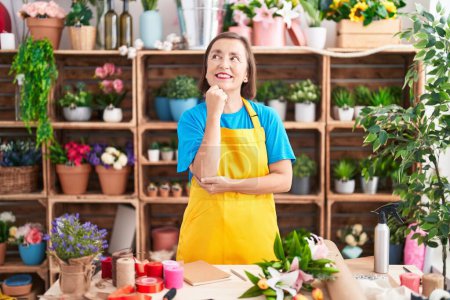 Photo for Middle age hispanic woman working at florist shop thinking concentrated about doubt with finger on chin and looking up wondering - Royalty Free Image