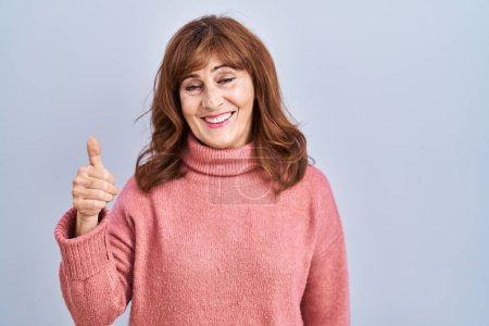 Téléchargez les photos : Middle age hispanic woman standing over isolated background doing happy thumbs up gesture with hand. approving expression looking at the camera showing success. - en image libre de droit