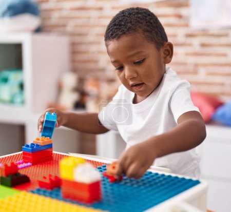 Photo for African american boy playing with construction blocks sitting on table at kindergarten - Royalty Free Image