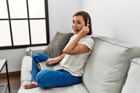 Foto de Mujer hispana de mediana edad sentada en el sofá con auriculares en casa - Imagen libre de derechos
