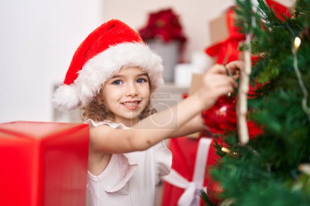 Téléchargez les photos : Adorable fille caucasienne souriant décoration confiante arbre de Noël à la maison - en image libre de droit