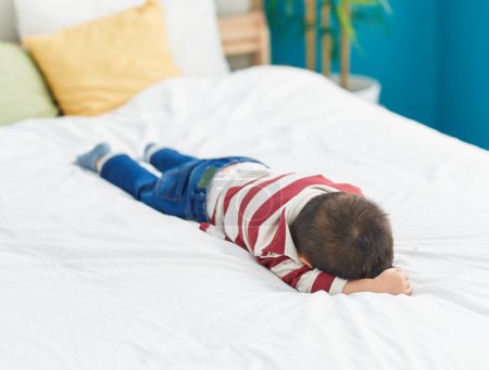 Foto de Adorable niño acostado en la cama llorando en el dormitorio - Imagen libre de derechos